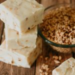 stack of health bar fudge with granola scattered on the table and in a bowl