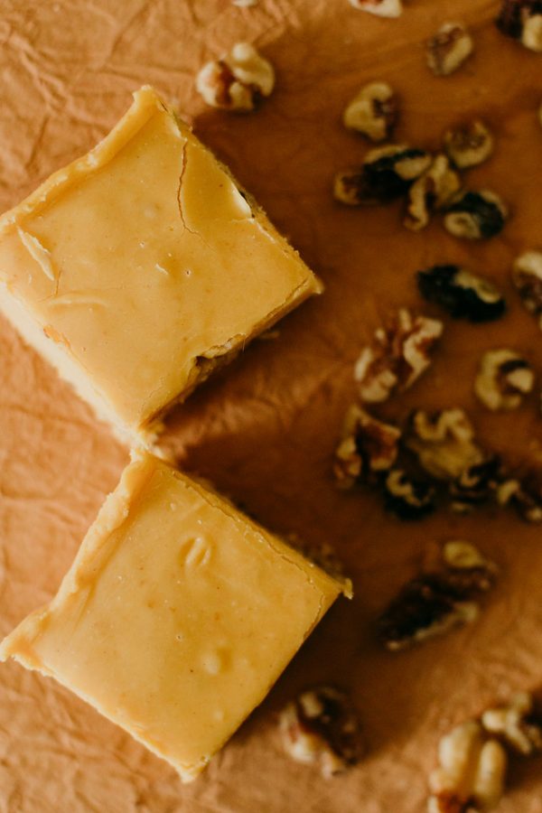 a couple pumpkin walnut fudge squares surrounded by walnuts