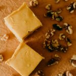 a couple pumpkin walnut fudge squares surrounded by walnuts