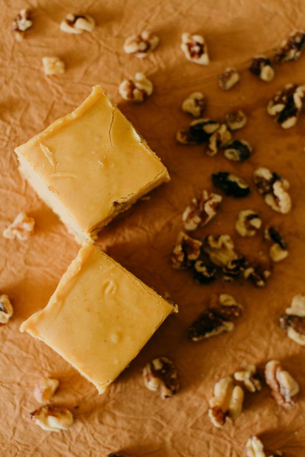 a couple pumpkin walnut fudge squares surrounded by walnuts