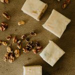 vanilla walnut fudge in a row on a table surrounded by walnuts